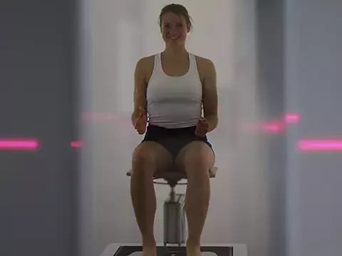 WOmen in body scanner sitting on a stool